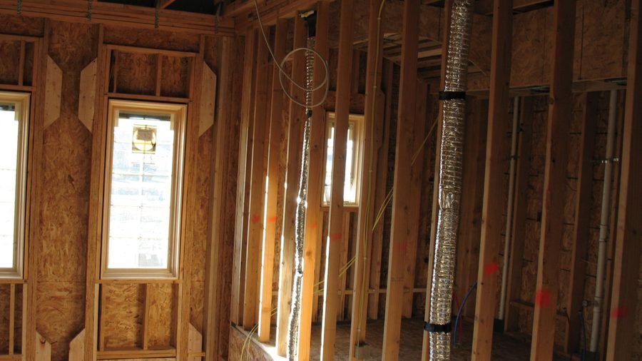 Exposed HVAC ductwork installed between wall framing in a home.