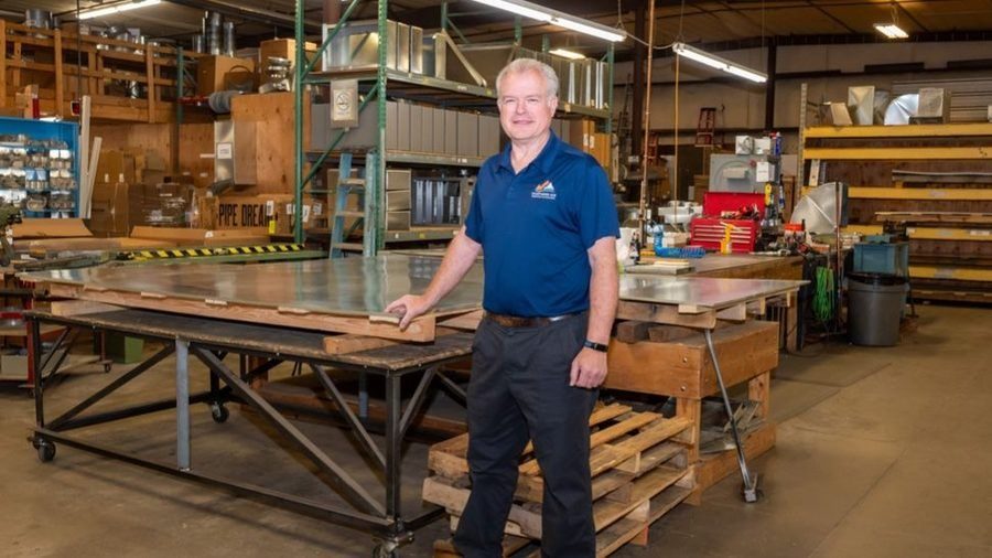 Commercial HVAC professional standing inside a sheet metal fabrication shop.
